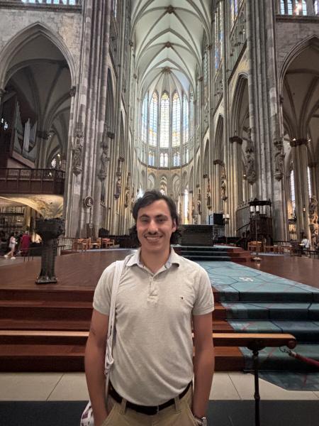 A photo of me standing by the altar of the Kölner Dom, wearing a grey polo and smiling.