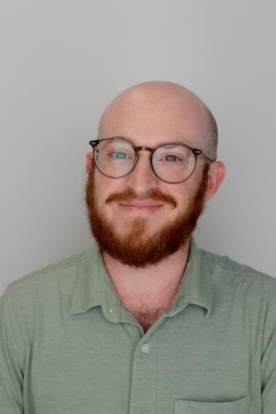 smiling man with glasses and red beard wearing green shirt 