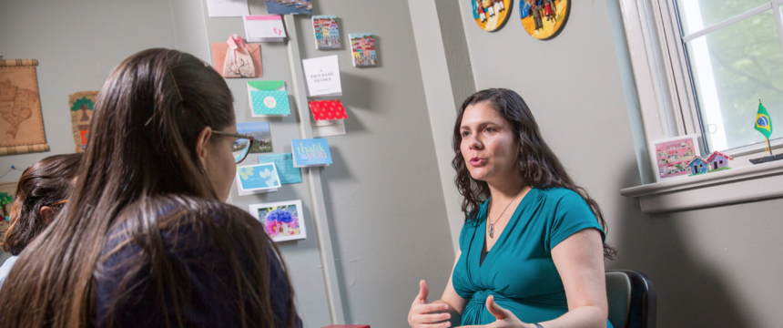 Graduate student Lunara Goncalves interacts with professor Cecilia Rodrigues inside an office.