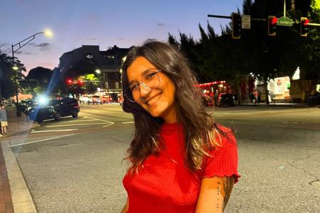 A woman wearing a red blouse and glasses smiles for a picture