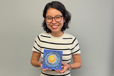 Késsia Shingu smiling and holding a paint. 