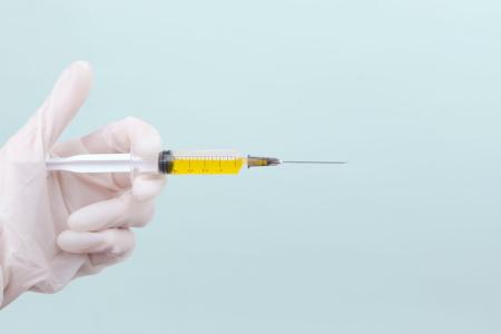 Image of a gloved hand holding a syringe