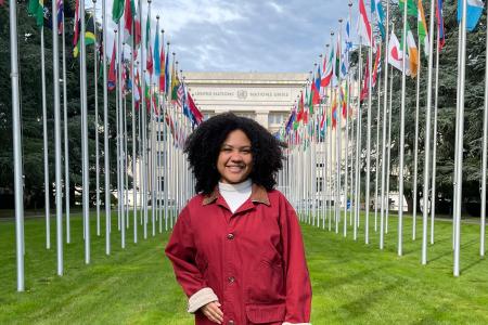 Picture of a woman wearing a red coat in front of the United Nations Building