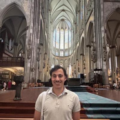 A photo of me standing by the altar of the Kölner Dom, wearing a grey polo and smiling.