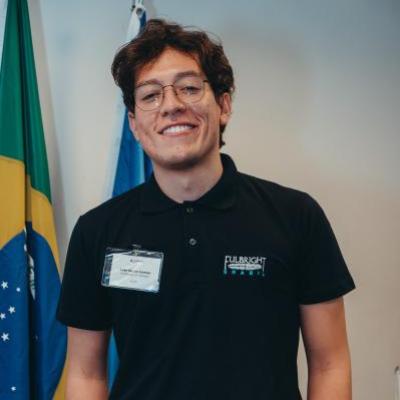 Joao Pedro stands smiling before the Brazilian flag.