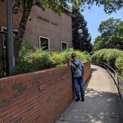 man standing if front of gilbert hall building